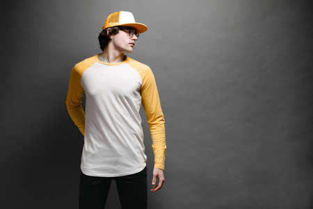 Man model with beard wearing white and yellow blank Long Sleeve Shirt for mock up and a baseball cap with space for your  design over gray backgroundの写真素材