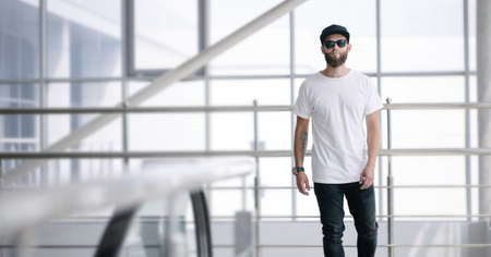 Hipster handsome male model with glasses wearing white blank t-shirt and black jeans with space for your   or design in casual urban styleの写真素材