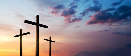 Easter concept. Cross of Jesus Christ empty over dramatic sunrise sky panorama with sclouds.の写真素材
