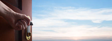 Open door to the sky. Hand opening a door to new opportunitiesの写真素材