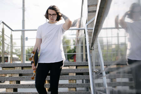Hipster handsome male model wearing white blank t-shirt with space for your logo or design in casual urban styleの写真素材