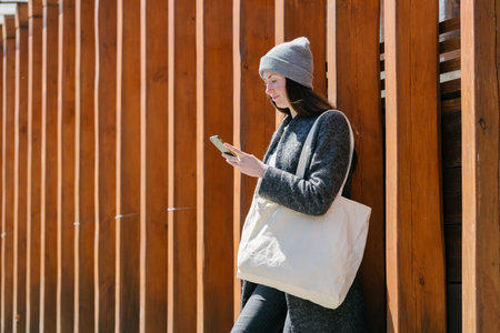 Woman holding white textile tote eco bag in urban area. Ecology or environment protection concept. White eco bag for mock up.の写真素材