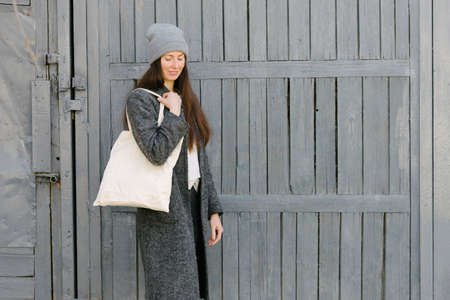 Woman holding white textile tote eco bag in urban area. Ecology or environment protection concept. White eco bag for mock up.の写真素材
