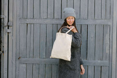 Woman holding white textile tote eco bag in urban area. Ecology or environment protection concept....
