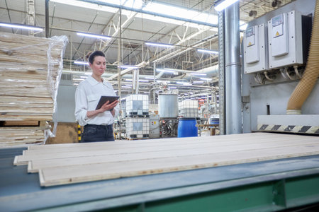 Business woman worker in the carpentry factory using tablet pc. Carpentry factory. Factory for the production of parquet boardの写真素材