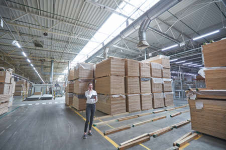 Business woman in Industrial Carpentry factory - production of wooden boards with modern machinesの写真素材