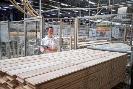 Business woman in the carpentry factory using tablet pc. Carpentry factory. Factory for the production of parquet boardの写真素材