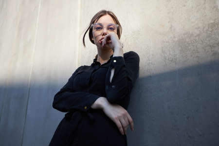 Fashion headshot of a sexy brunette woman with a make up wearing black clothes outside in urban area at sunsetの写真素材