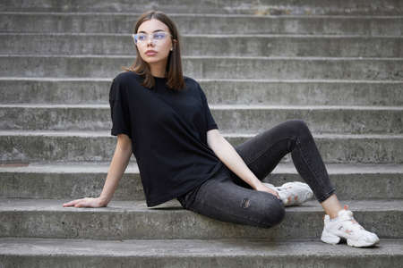 Woman or girl wearing black blank cotton t-shirt with space for your logo, mock up or design in casual urban styleの写真素材
