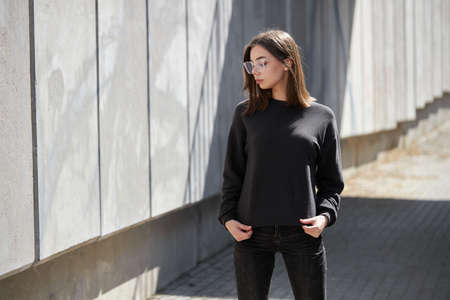 Woman wearing black sweatshirt or hoodie for mock up, logo designs or design prints with with free space on the city streets.の写真素材