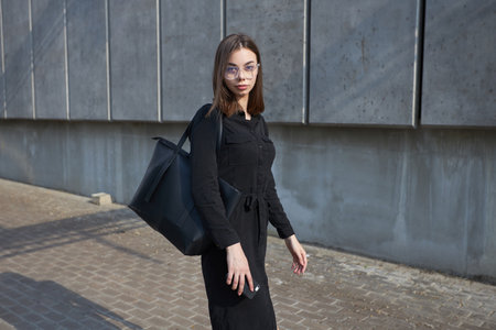 Sexy business brunette woman with a make up wearing black clothes She is walking on city cement...