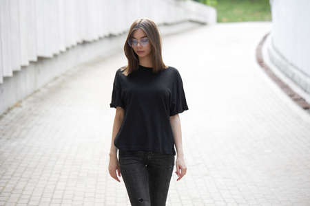 Woman or girl wearing black blank cotton t-shirt with space for your logo, mock up or design in casual urban styleの写真素材