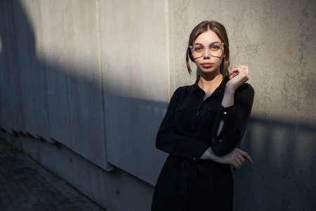 Fashion headshot of a sexy brunette woman with a make up wearing black clothes outside in urban area at sunsetの写真素材