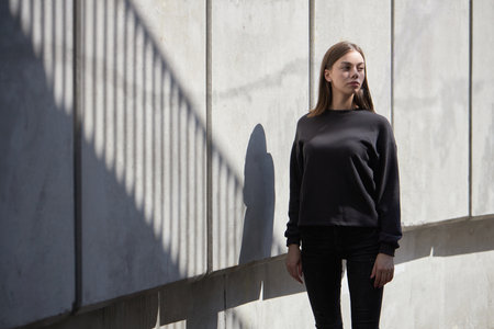 Woman wearing black sweatshirt or hoodie for mock up, logo designs or design prints with with free space on the city streets.の写真素材