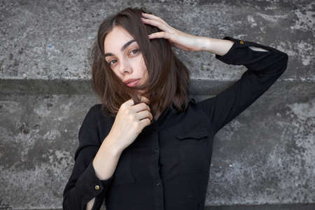 Fashion headshot of a sexy brunette woman with a make up wearing black dress in urban areaの写真素材