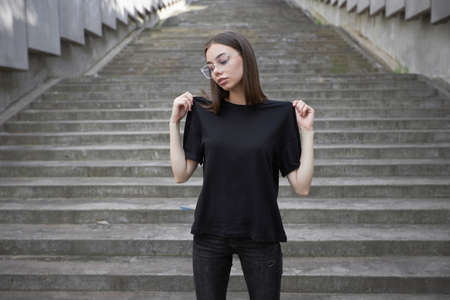 Woman or girl wearing black blank cotton t-shirt with space for your logo, mock up or design in casual urban styleの写真素材