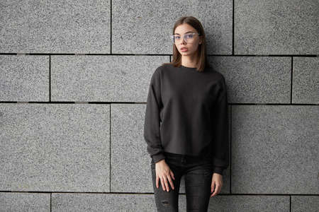 Woman wearing black sweatshirt or hoodie for mock up, logo designs or design prints with with free space on the city streets.の写真素材