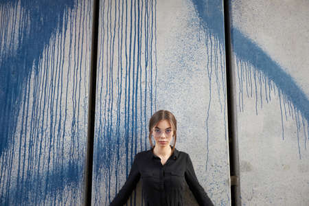 Fashion headshot of a sexy brunette woman with a make up wearing black clothes outside in urban area at sunsetの写真素材