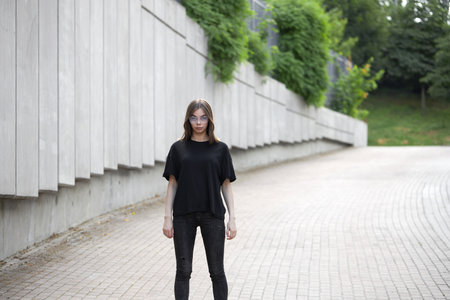 Fashion portrait of a sexy brunette woman with a make up wearing black clothes. She is wearing black modern dress, white sneakers and glassesの写真素材