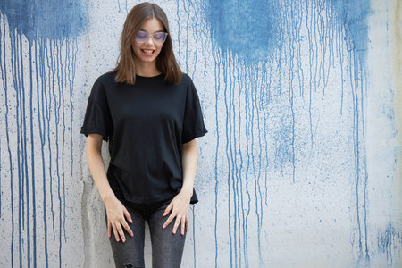 Fashion portrait of a sexy brunette woman with a make up wearing black clothes. She is wearing black modern dress, white sneakers and glassesの写真素材