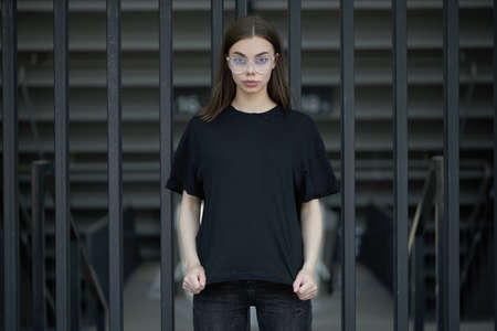 Fashion portrait of a sexy brunette woman with a make up wearing black clothes. She is wearing black modern dress, white sneakers and glassesの写真素材