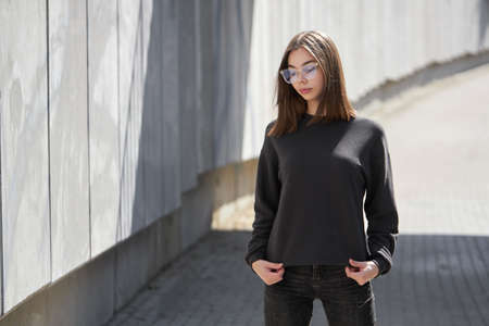 Woman wearing black sweatshirt or hoodie for mock up, logo designs or design prints with with free space on the city streets.の写真素材