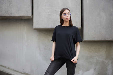 Woman or girl wearing black blank cotton t-shirt with space for your logo, mock up or design in casual urban styleの写真素材