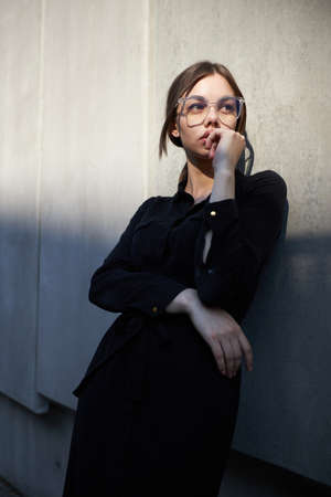 Fashion headshot of a sexy brunette woman with a make up wearing black clothes outside in urban area at sunsetの写真素材