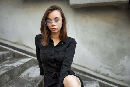 Fashion headshot of a sexy brunette woman with a make up wearing black dress in urban areaの写真素材