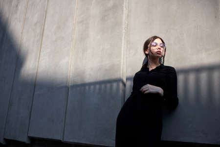 Fashion headshot of a sexy brunette woman with a make up wearing black clothes outside in urban area at sunsetの写真素材