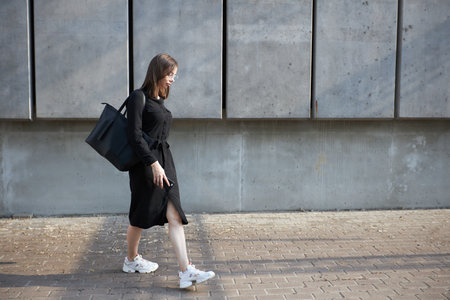 Sexy business brunette woman with a make up wearing black clothes She is walking on city cement streetsの写真素材