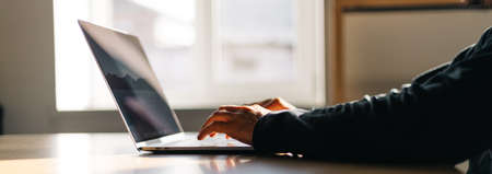Office workspace. Table with a man working on a laptop over wooden tableの写真素材