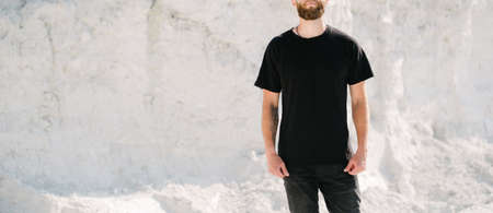 Hipster handsome male model with beard wearing black blank t-shirt with space for your logo or design in casual urban styleの写真素材