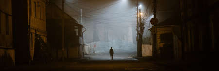 Lonely woman walking in a foggy old city in city street lightsの写真素材