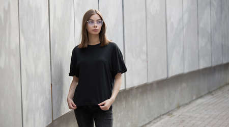 Woman or girl wearing black blank cotton t-shirt with space for your logo, mock up or design in casual urban styleの写真素材
