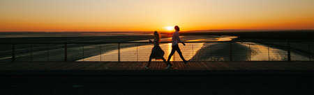 Couple walking next to a river during sunsetの写真素材