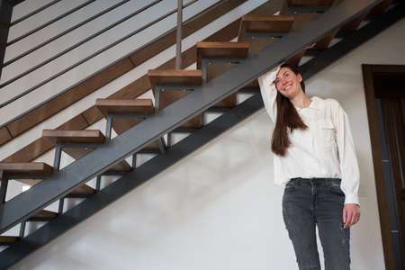 Woman standing next to a modern staircase in scandinavian style houseの写真素材