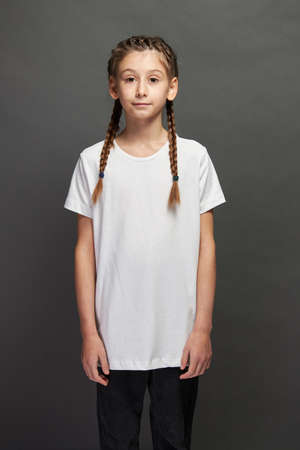 Kid girl wearing white t-shirt with space for your logo or design in studio over gray backgroundの写真素材