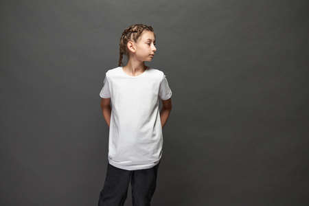 Kid girl wearing white t-shirt with space for your logo or design in studio over gray backgroundの写真素材