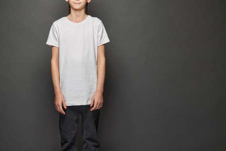 Kid girl wearing white t-shirt with space for your logo or design in studio over gray backgroundの写真素材
