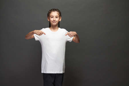 Kid girl wearing white t-shirt with space for your logo or design in studio over gray backgroundの写真素材