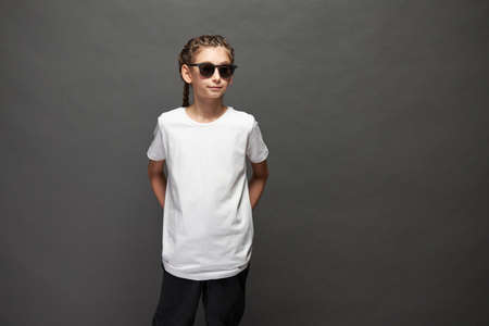 Kid girl wearing white t-shirt with space for your logo or design in studio over gray backgroundの写真素材