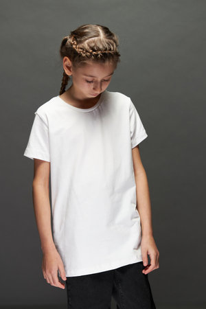 Kid girl wearing white t-shirt with space for your logo or design in studio over gray backgroundの写真素材