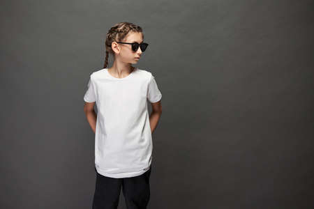 Kid girl wearing white t-shirt with space for your logo or design in studio over gray backgroundの写真素材