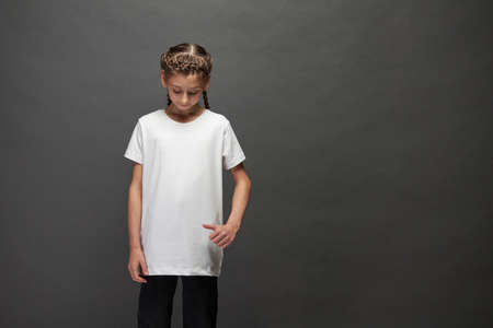 Kid girl wearing white t-shirt with space for your logo or design in studio over gray backgroundの写真素材