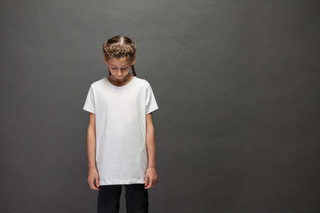 Kid girl wearing white t-shirt with space for your logo or design in studio over gray backgroundの写真素材