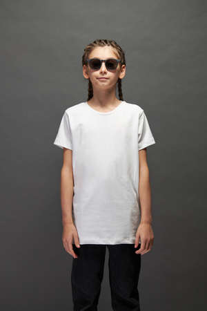 Kid girl wearing white t-shirt with space for your logo or design in studio over gray backgroundの写真素材