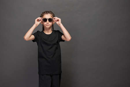 Kid girl wearing black t-shirt with space for your logo or design in studio over gray backgroundの写真素材