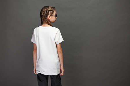 Kid girl wearing white t-shirt with space for your logo or design in studio over gray backgroundの写真素材