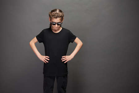 Kid girl wearing black t-shirt with space for your logo or design in studio over gray backgroundの写真素材